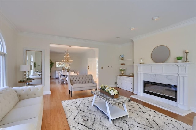 living area featuring a healthy amount of sunlight, wood finished floors, a fireplace, ornamental molding, and a chandelier