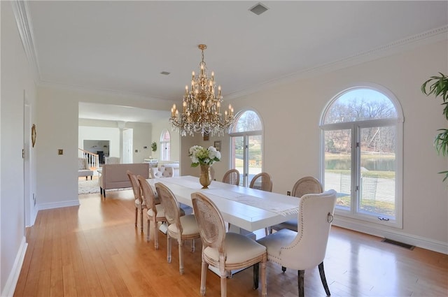 dining space featuring visible vents, a chandelier, ornamental molding, and light wood finished floors