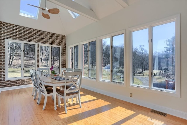 sunroom / solarium with vaulted ceiling with skylight, visible vents, and ceiling fan