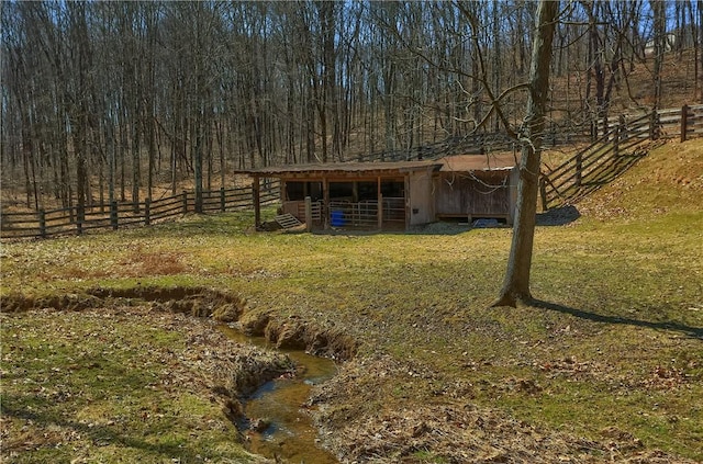 view of yard with an outdoor structure, a wooded view, and an exterior structure