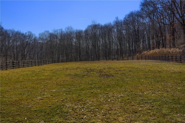 view of yard featuring a wooded view and fence