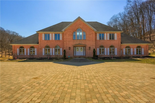 view of front facade with french doors, brick siding, and roof with shingles