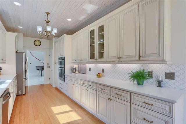 kitchen with glass insert cabinets, light wood-style floors, tasteful backsplash, and stainless steel appliances