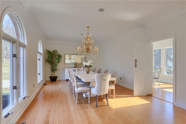 dining area with baseboards, a notable chandelier, light wood-style flooring, and crown molding