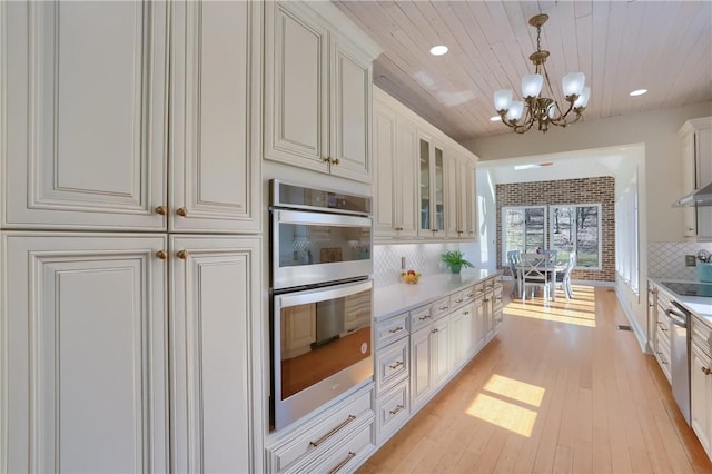 5125 Bear Run Rd, Cranberry Twp, PA 16066 - kitchen featuring appliances with stainless steel finishes, a chandelier, decorative backsplash, light countertops, and glass insert cabinets
