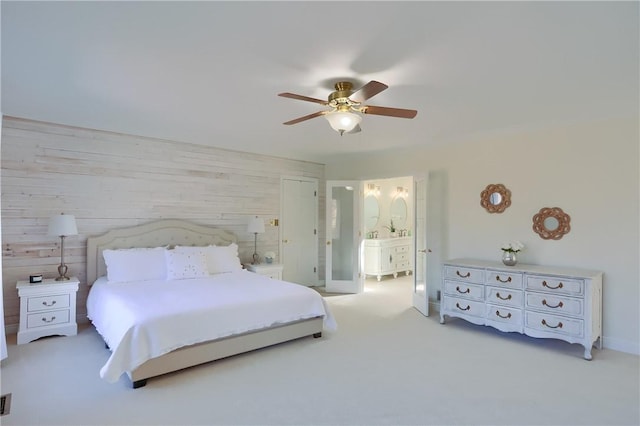 carpeted bedroom with ensuite bath, a ceiling fan, baseboards, and wood walls