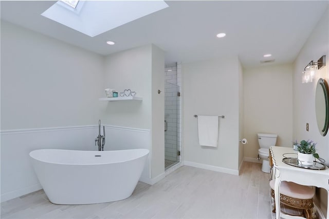 bathroom with a shower stall, toilet, a skylight, a soaking tub, and vanity