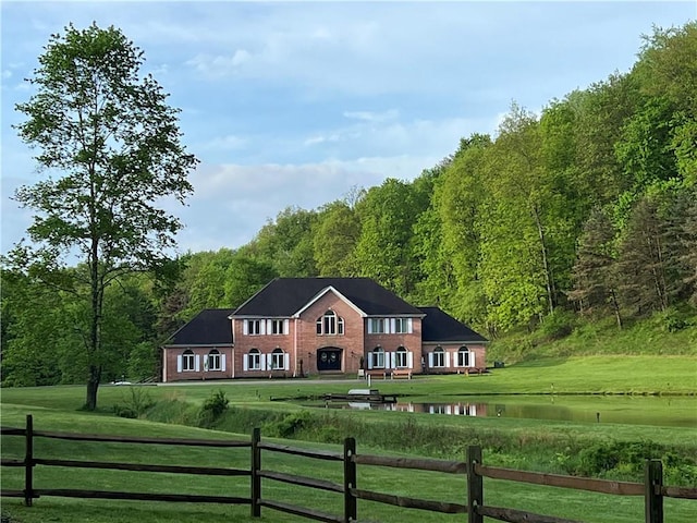 view of front of property featuring a front yard, a view of trees, and fence