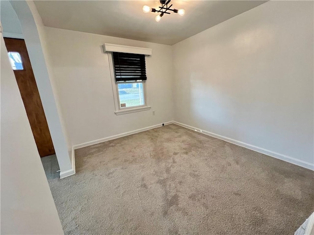 unfurnished room featuring arched walkways, baseboards, and carpet floors