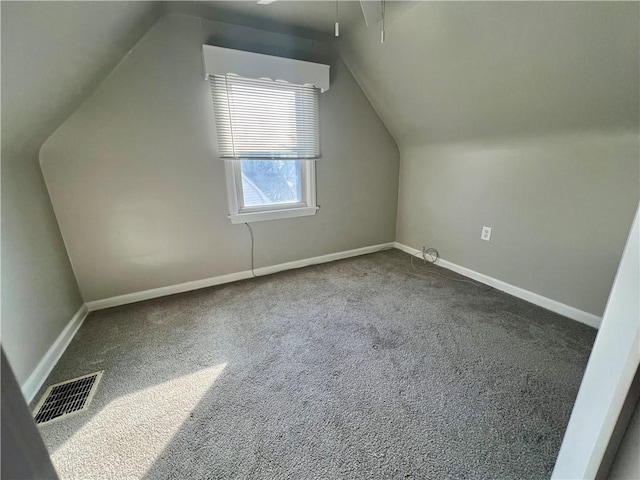 additional living space with visible vents, carpet floors, baseboards, and vaulted ceiling