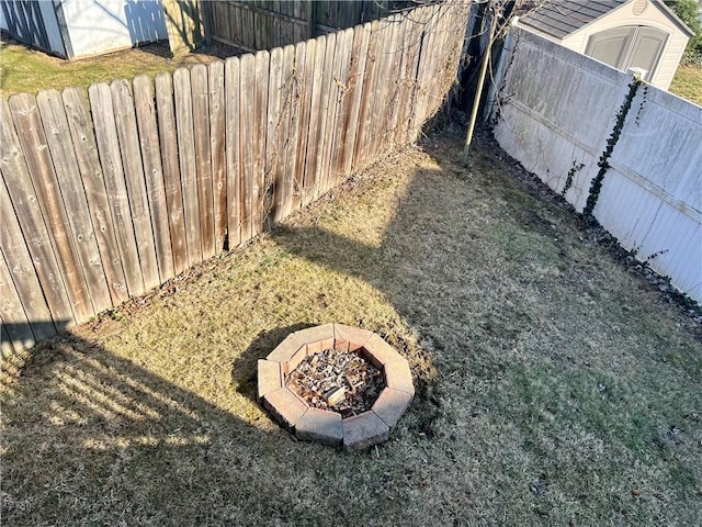 view of yard with a fire pit, an outdoor structure, a shed, and fence