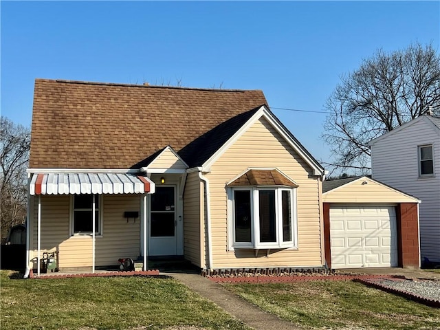 view of front of property with an attached garage, a shingled roof, and a front yard