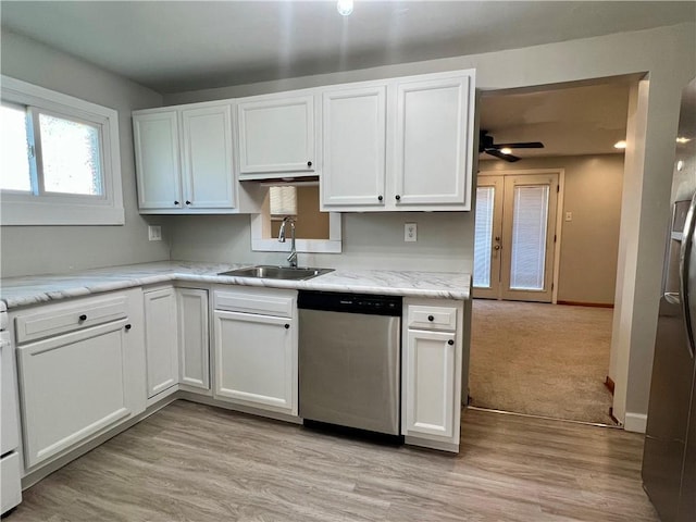 kitchen featuring light stone countertops, a sink, white cabinets, light wood-style floors, and appliances with stainless steel finishes