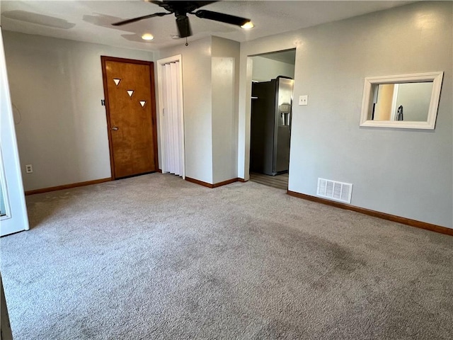 carpeted spare room with baseboards, visible vents, and ceiling fan