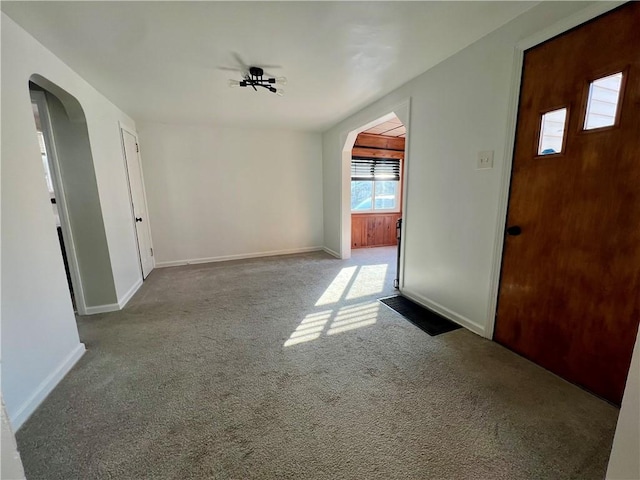 foyer with baseboards, arched walkways, and carpet flooring