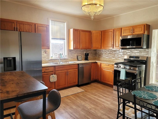 kitchen featuring a sink, stainless steel appliances, crown molding, light countertops, and a chandelier