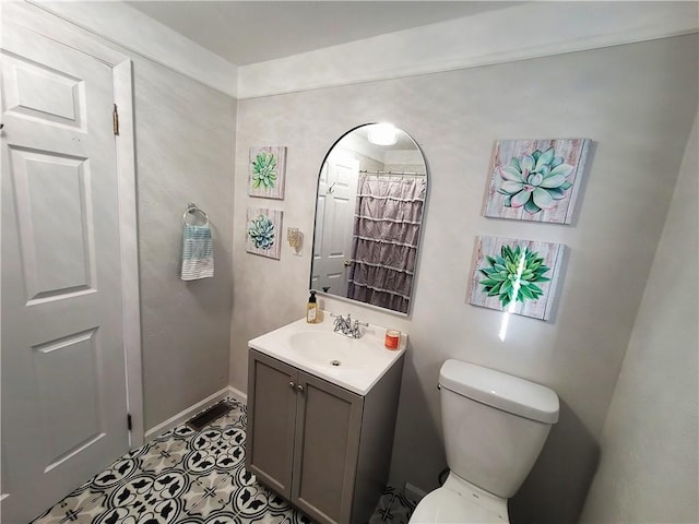 bathroom with toilet, vanity, and baseboards