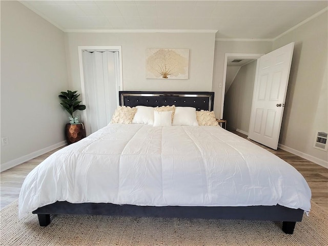 bedroom featuring baseboards, wood finished floors, and crown molding