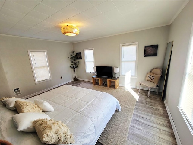 bedroom featuring crown molding, wood finished floors, and baseboards