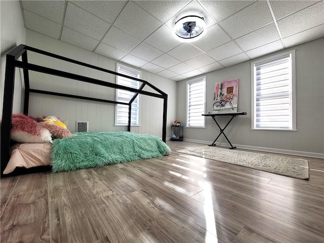 bedroom with wood finished floors, baseboards, and a paneled ceiling