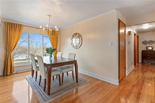 dining area with baseboards, visible vents, an inviting chandelier, crown molding, and light wood-type flooring