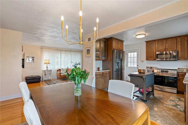 dining room featuring light wood finished floors, visible vents, crown molding, baseboards, and a chandelier