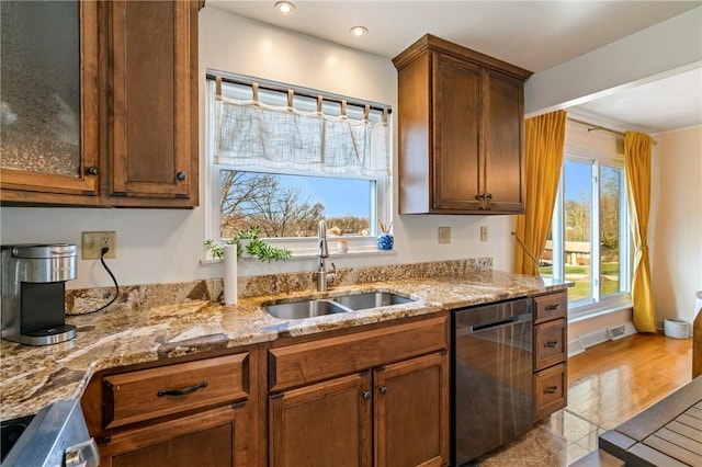 kitchen with dishwasher, light stone countertops, a wealth of natural light, and a sink