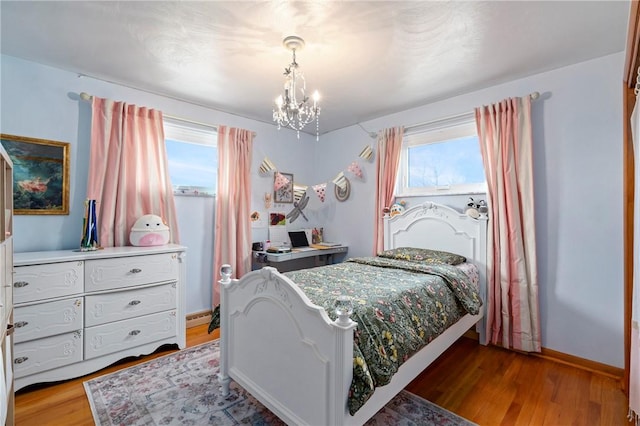 bedroom with wood finished floors, baseboards, and a chandelier