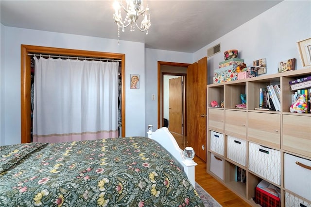 bedroom with a chandelier, visible vents, and light wood-style flooring