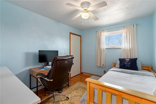 bedroom featuring a baseboard radiator, wood finished floors, a closet, and ceiling fan