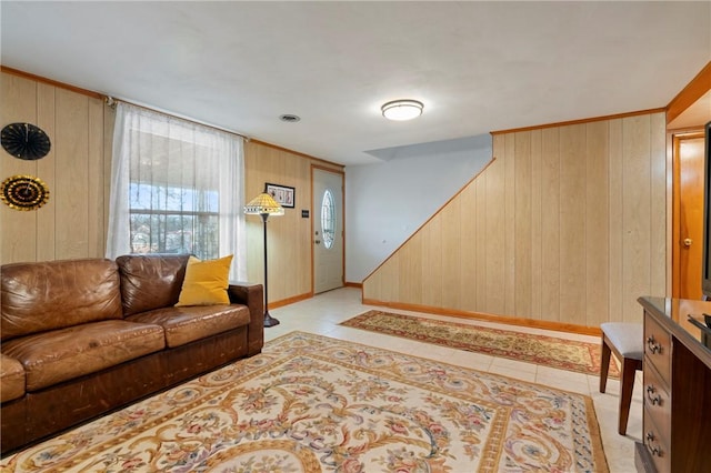 living room with light tile patterned floors, stairway, baseboards, and wooden walls