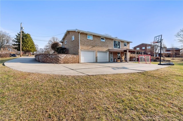 back of house with an attached garage, concrete driveway, and a yard