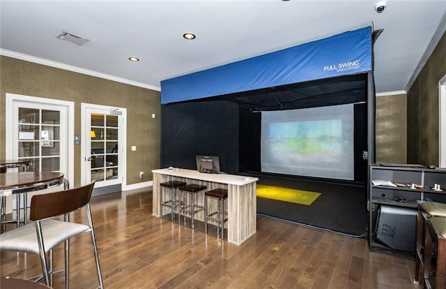 interior space with dark wood finished floors, crown molding, golf simulator, and visible vents