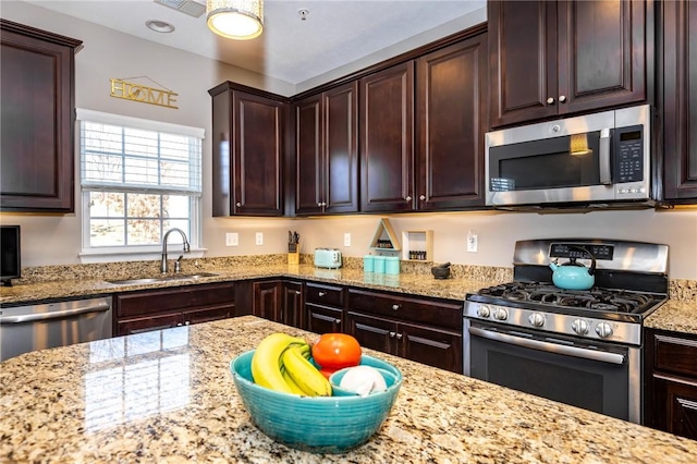 kitchen with a sink, dark brown cabinetry, light stone counters, and stainless steel appliances