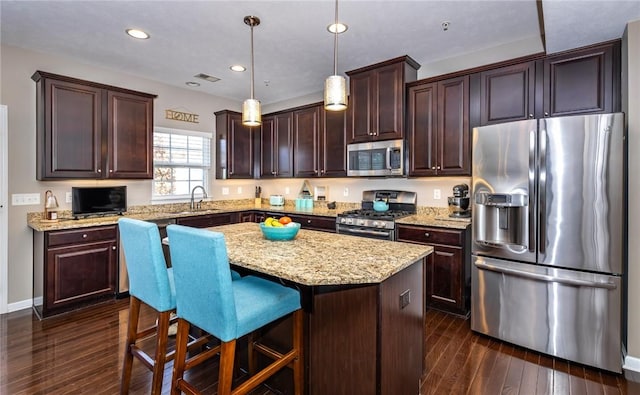 kitchen featuring visible vents, a sink, stainless steel appliances, dark brown cabinets, and dark wood-style flooring