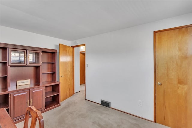 unfurnished office with light carpet, visible vents, and baseboards