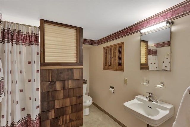 bathroom featuring toilet, baseboards, and a sink