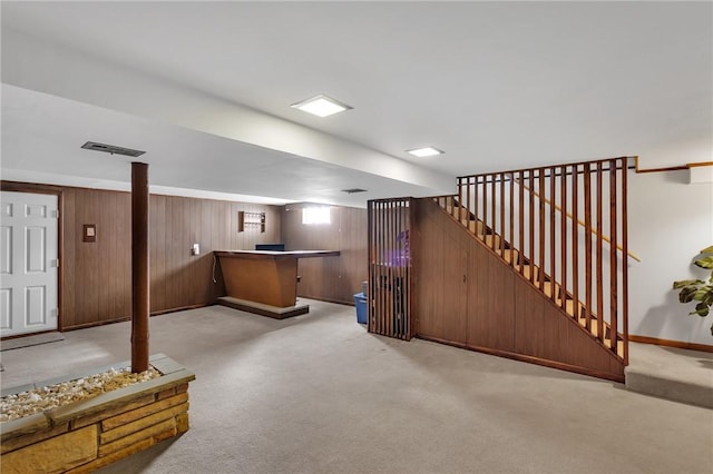 basement featuring wood walls, a dry bar, baseboards, and carpet