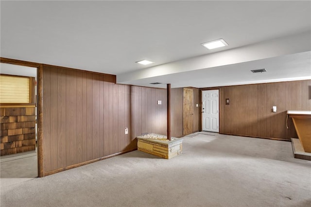 finished basement featuring visible vents, carpet, and wood walls