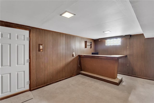 bar with a bar, wooden walls, and carpet flooring