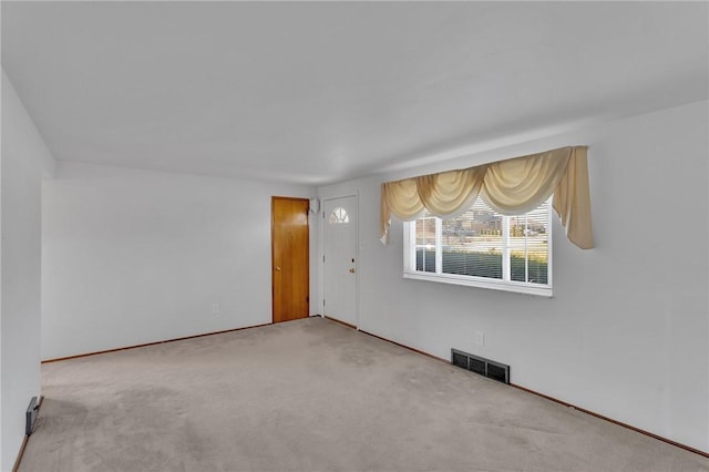 carpeted empty room featuring visible vents