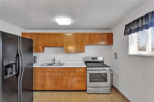 kitchen with brown cabinets, a sink, black fridge with ice dispenser, gas stove, and light countertops