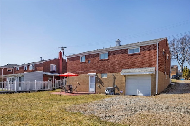 back of property with fence, an attached garage, a yard, a patio area, and brick siding