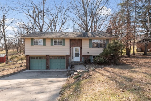 raised ranch with concrete driveway, an attached garage, brick siding, and a chimney