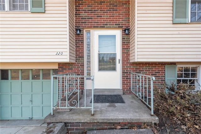 property entrance with brick siding and a garage