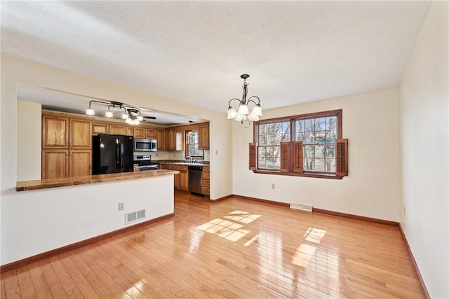 kitchen featuring visible vents, brown cabinets, appliances with stainless steel finishes, and light wood-type flooring