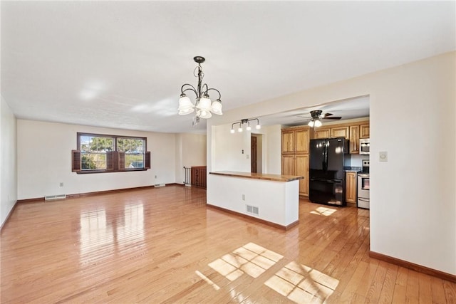 unfurnished living room with light wood-type flooring, visible vents, baseboards, and ceiling fan with notable chandelier