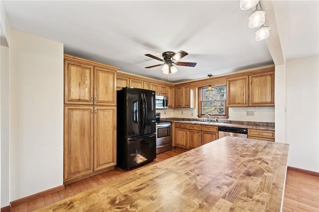 kitchen featuring baseboards, ceiling fan, a sink, appliances with stainless steel finishes, and light wood-type flooring