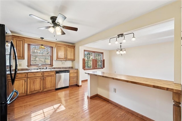 kitchen featuring freestanding refrigerator, a sink, light wood-style floors, dishwasher, and brown cabinets