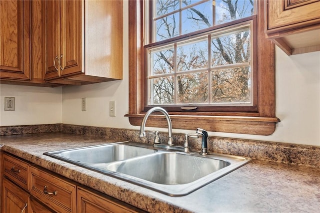 kitchen featuring plenty of natural light, brown cabinets, and a sink